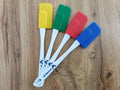 Four colorful spatulas on a wooden surface